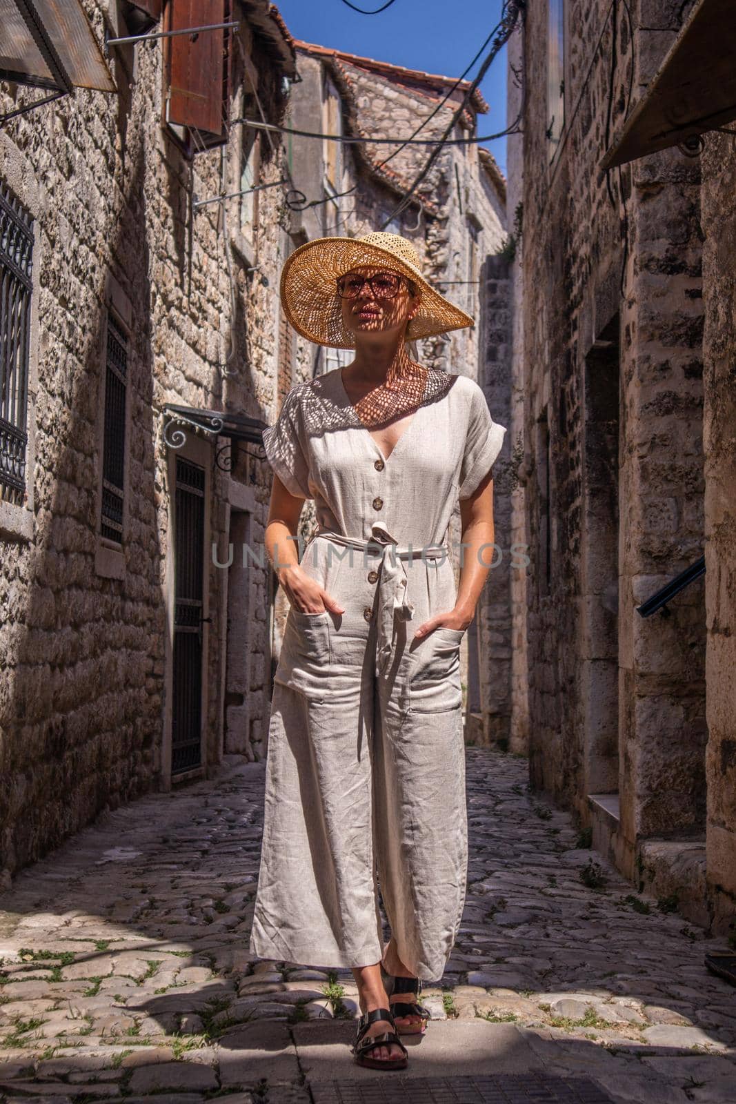 Beautiful blonde young female traveler wearing straw sun hat sightseeing and enjoying summer vacation in an old traditional costal town at Adriatic cost, Croatia. by kasto