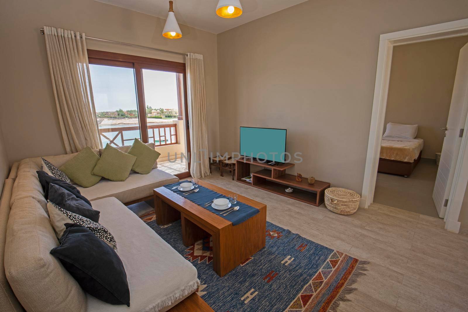 Living room lounge area in luxury apartment holiday show home showing interior design decor furnishing with balcony and bedroom