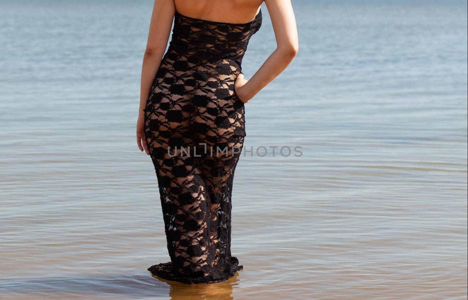 Young red-haired woman in a black lace dress on a naked body posing on the seashore