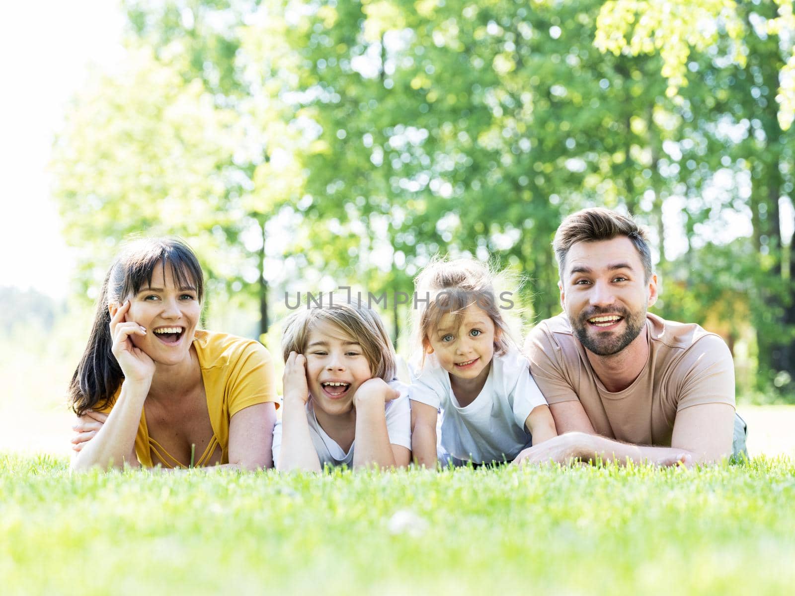 Family lying down in grass by ALotOfPeople