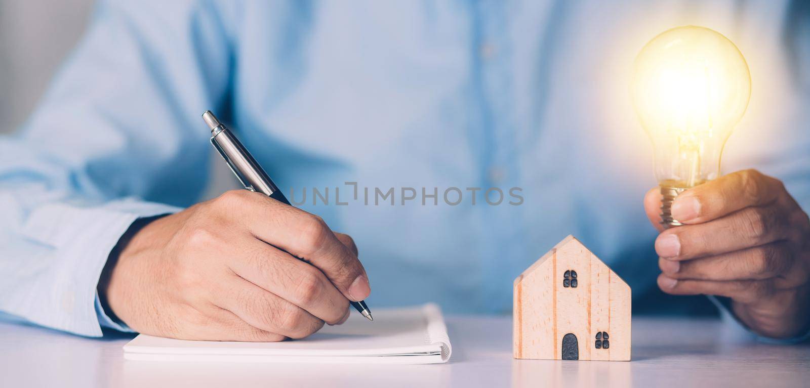 Businessman holding light bulb while home wooden for solution innovation and environment, thinking idea for planning buy house, residential with eco and saving energy, business and finance concept.
