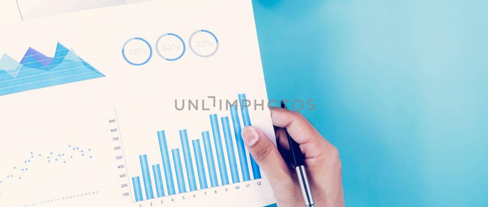Hand of businessman holding documents report statistic financial with graph and chart and laptop computer and coffee on desk, finance and invest, digital marketing, business and communication concept. by nnudoo