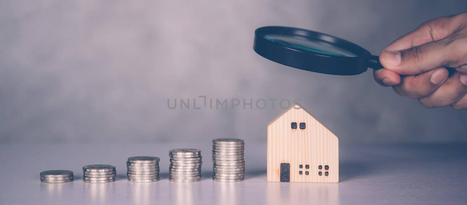 Hands of businessman holding magnifying glass home model with search real estate and property investment for profit, planning of residential and income, loan and mortgage, business concept. by nnudoo