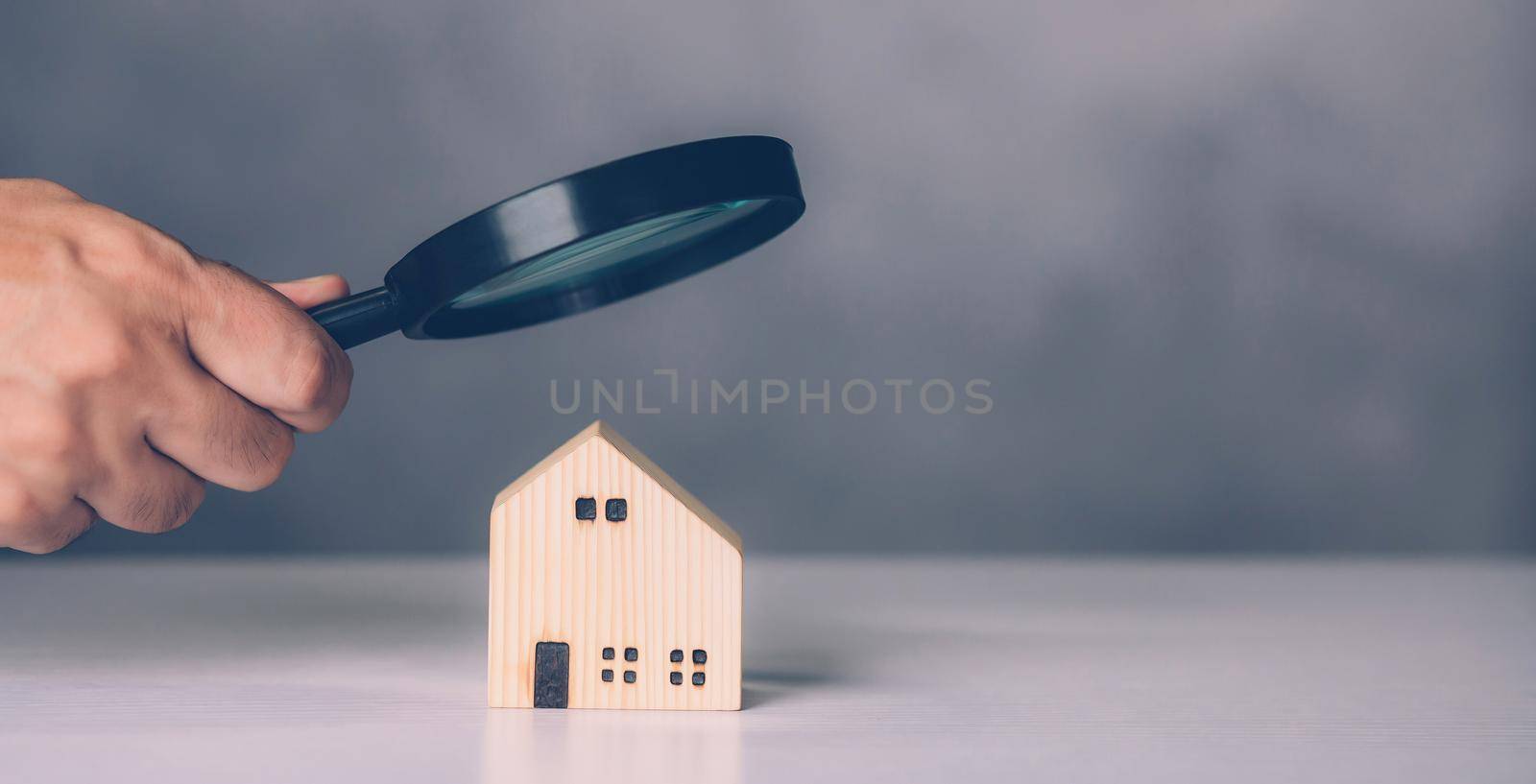 Hand of businessman hold magnifying glass looking house for examining and analyzing quality, inspection and check home, purchase and search residential and investment, business and property concept.