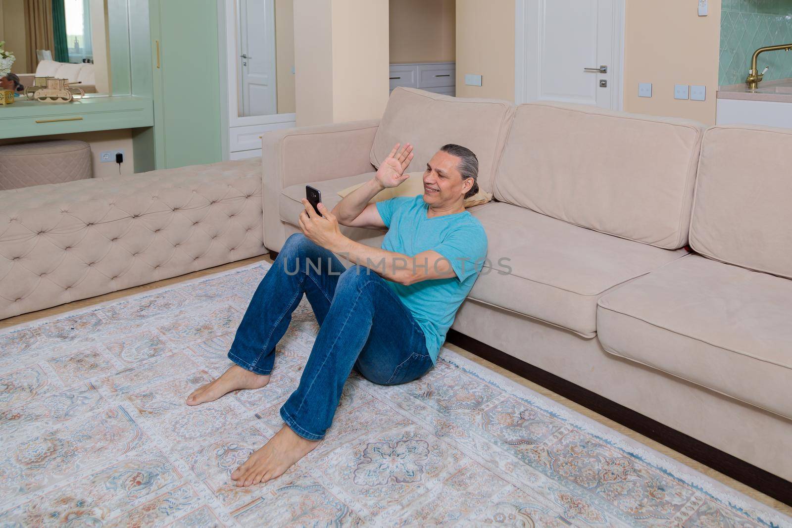 An adult man on the phone talking on video in an apartment.