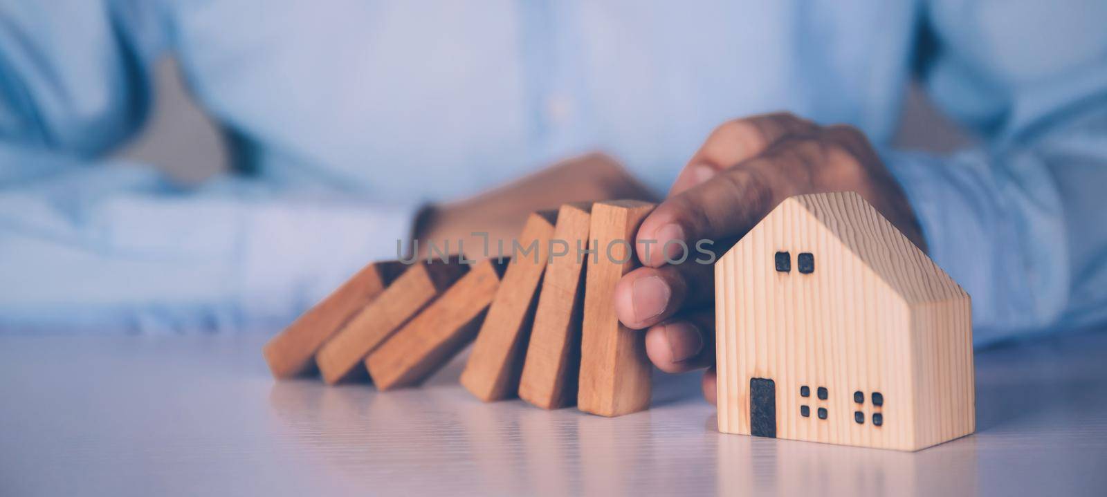 Hands of businessman stop risk about home with block wooden and safety, investment and insurance about real estate and property, planning and strategy, loan and debt of house, business concept.