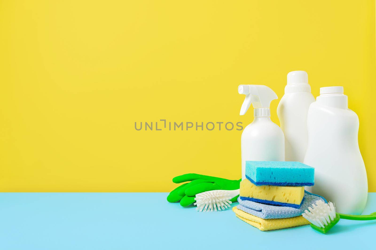 House cleaning products on yellow blue background, copy space. Cleaning service or housekeeping concept with space for text or design