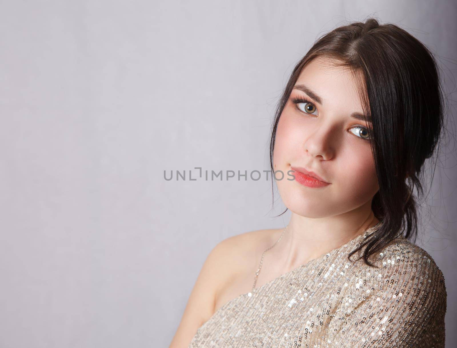 portrait of a young beautiful brunette girl in bright dress in studio on light background