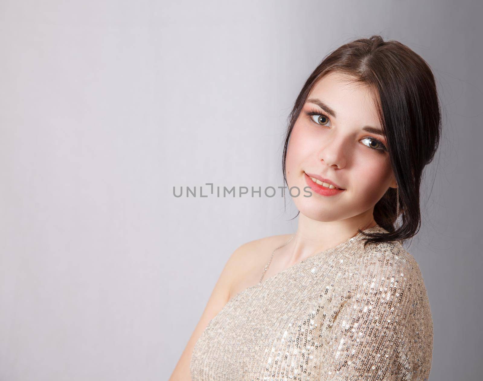 portrait of a young beautiful brunette girl in bright dress in studio on light background
