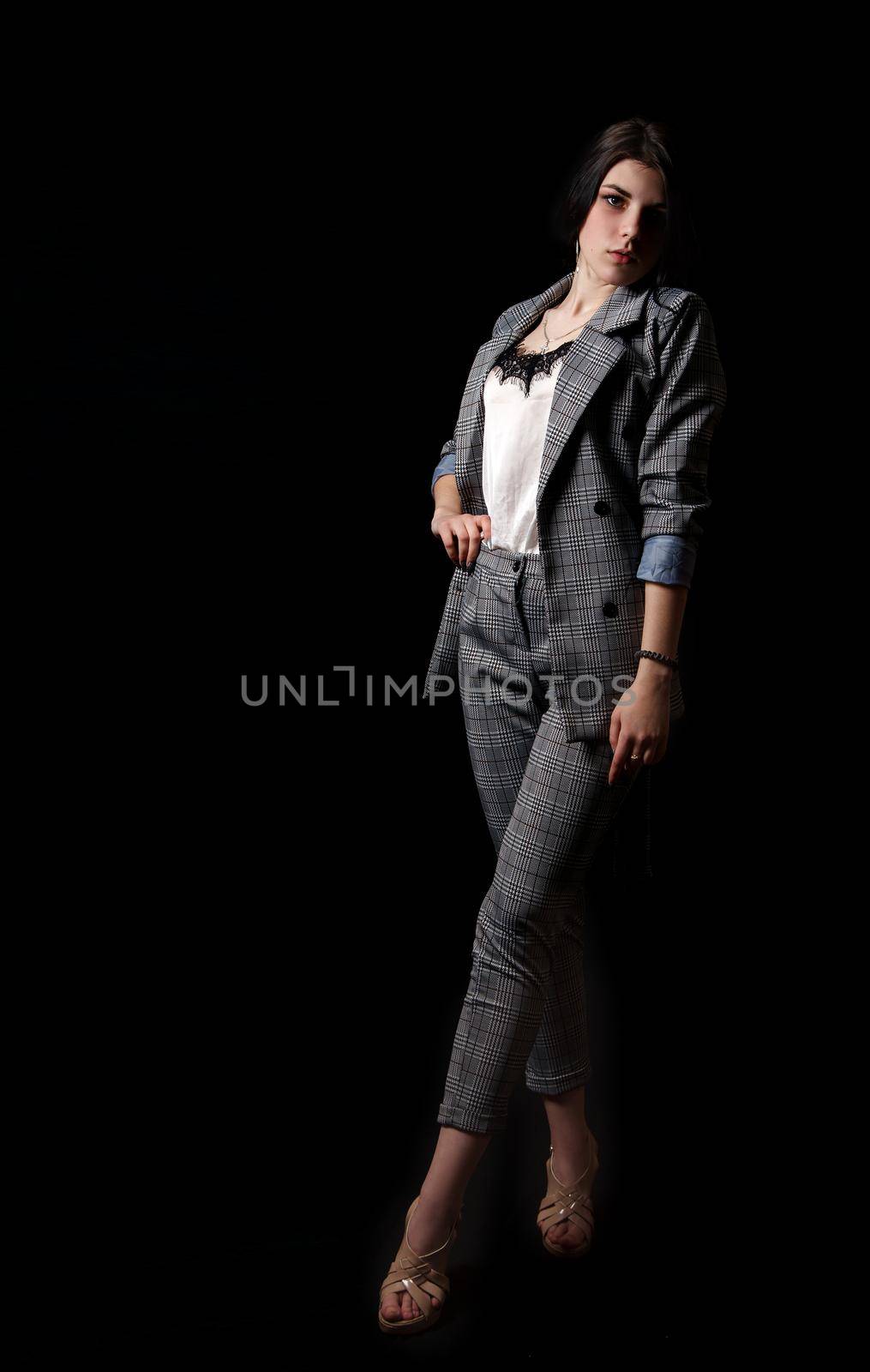 young beautiful girl in a business suit posing standing in the studio on black background