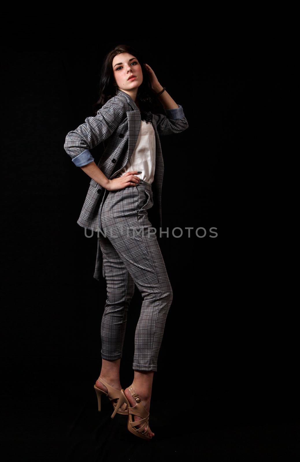 young beautiful girl in a business suit posing standing in the studio by raddnatt