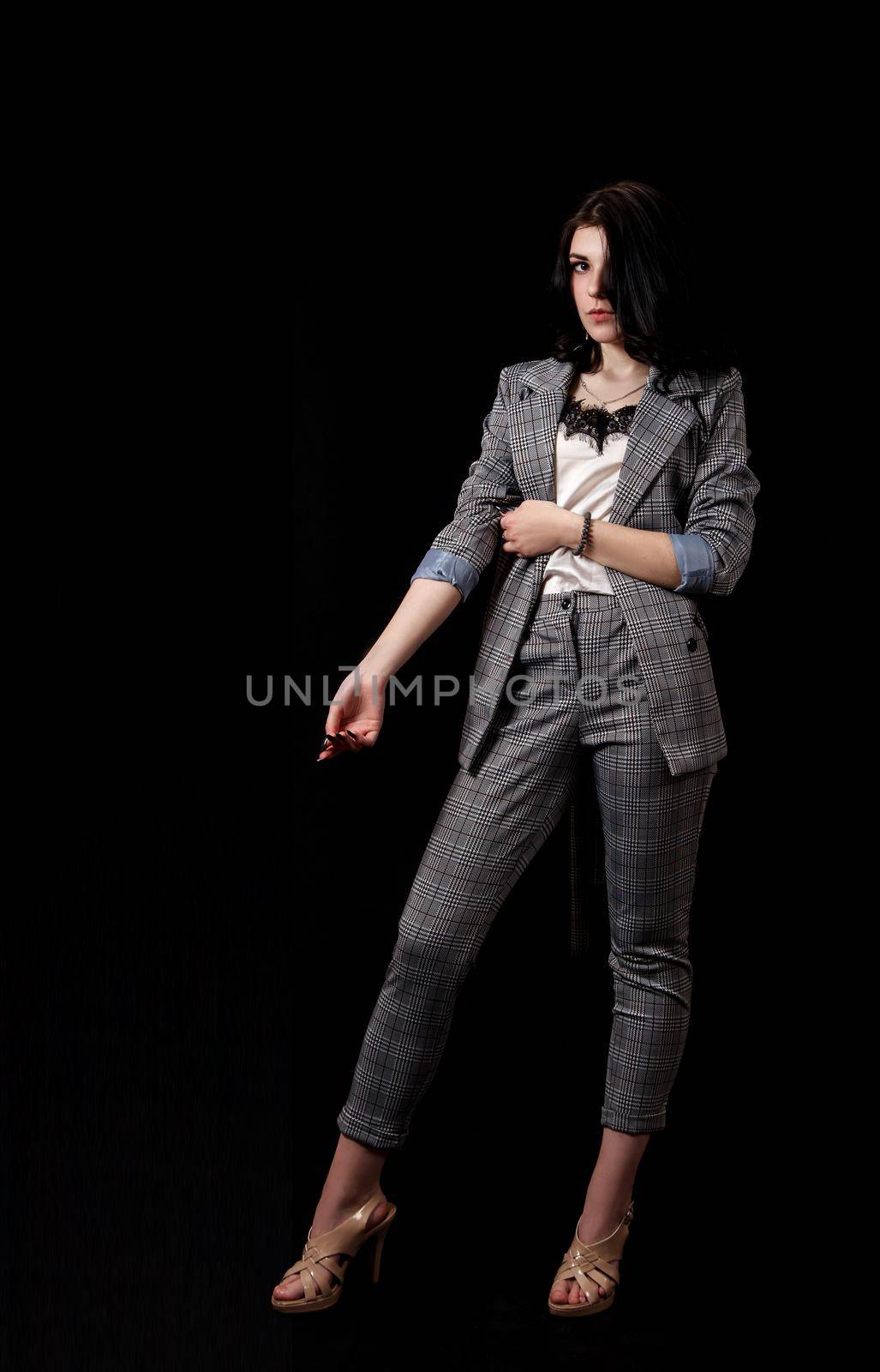 young beautiful girl in a business suit posing standing in the studio on black background