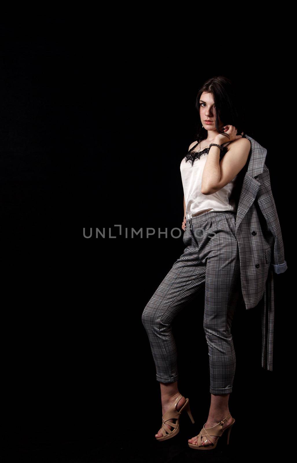 young beautiful girl in a business suit posing standing in the studio on black background