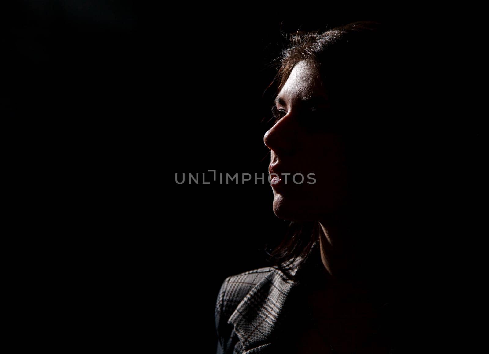 portrait of a young beautiful brunette girl in business suit in studio on black background