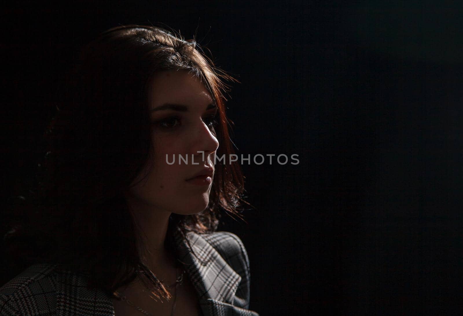 portrait of a young beautiful brunette girl in business suit in studio on black background