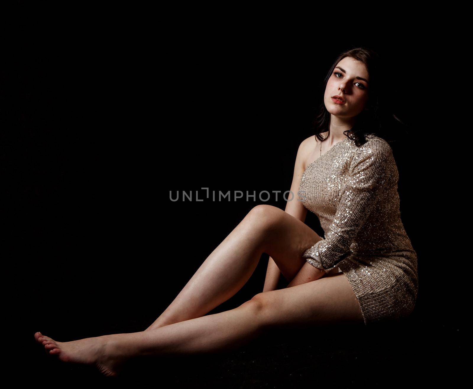 young beautiful girl posing sitting on floor in the studio by raddnatt