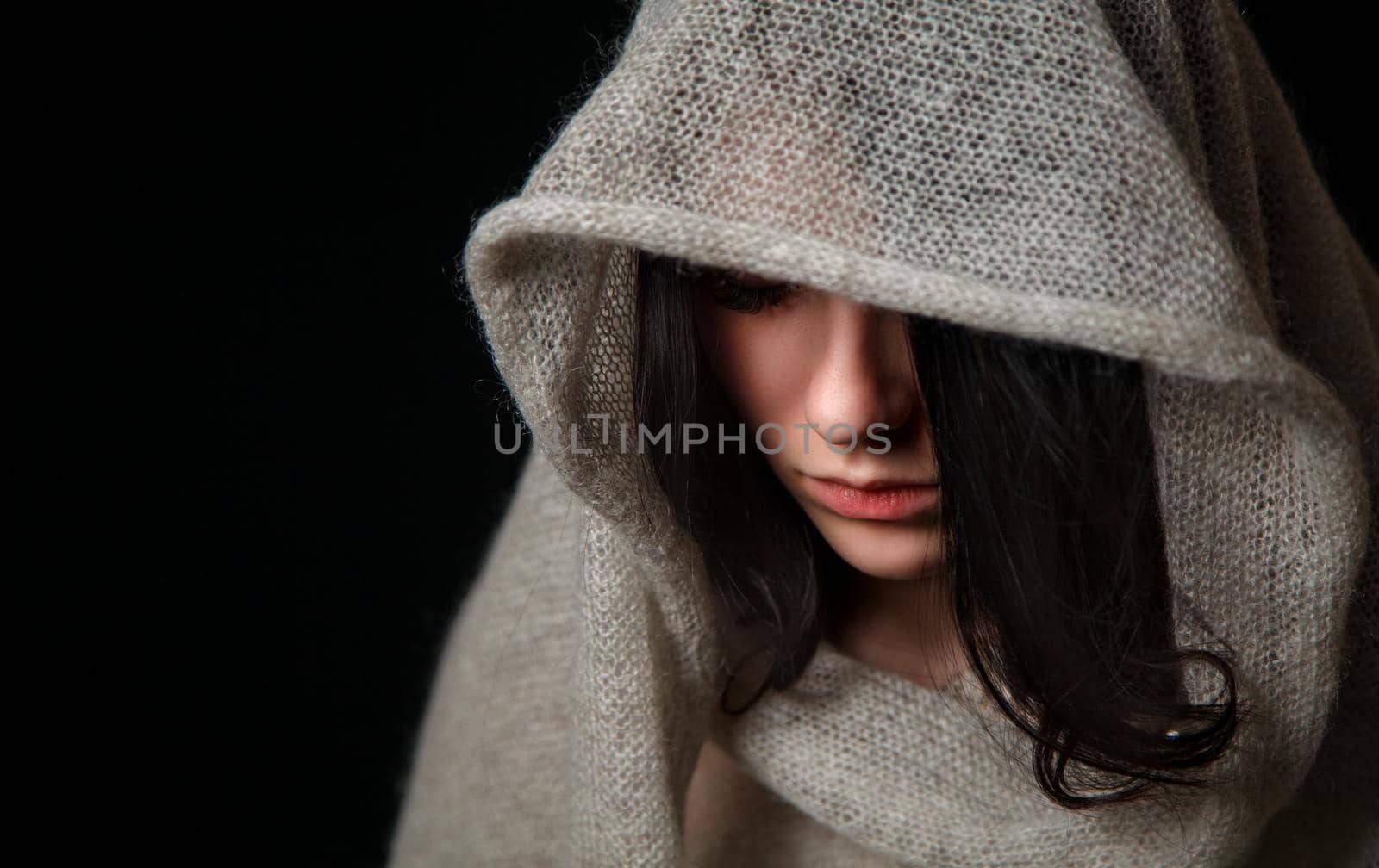 portrait of sad young beautiful girl in bright dress with scarf in studio on black background