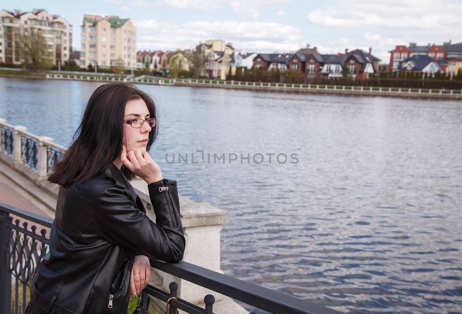 young girl stands on the embankment near lake in city park by raddnatt