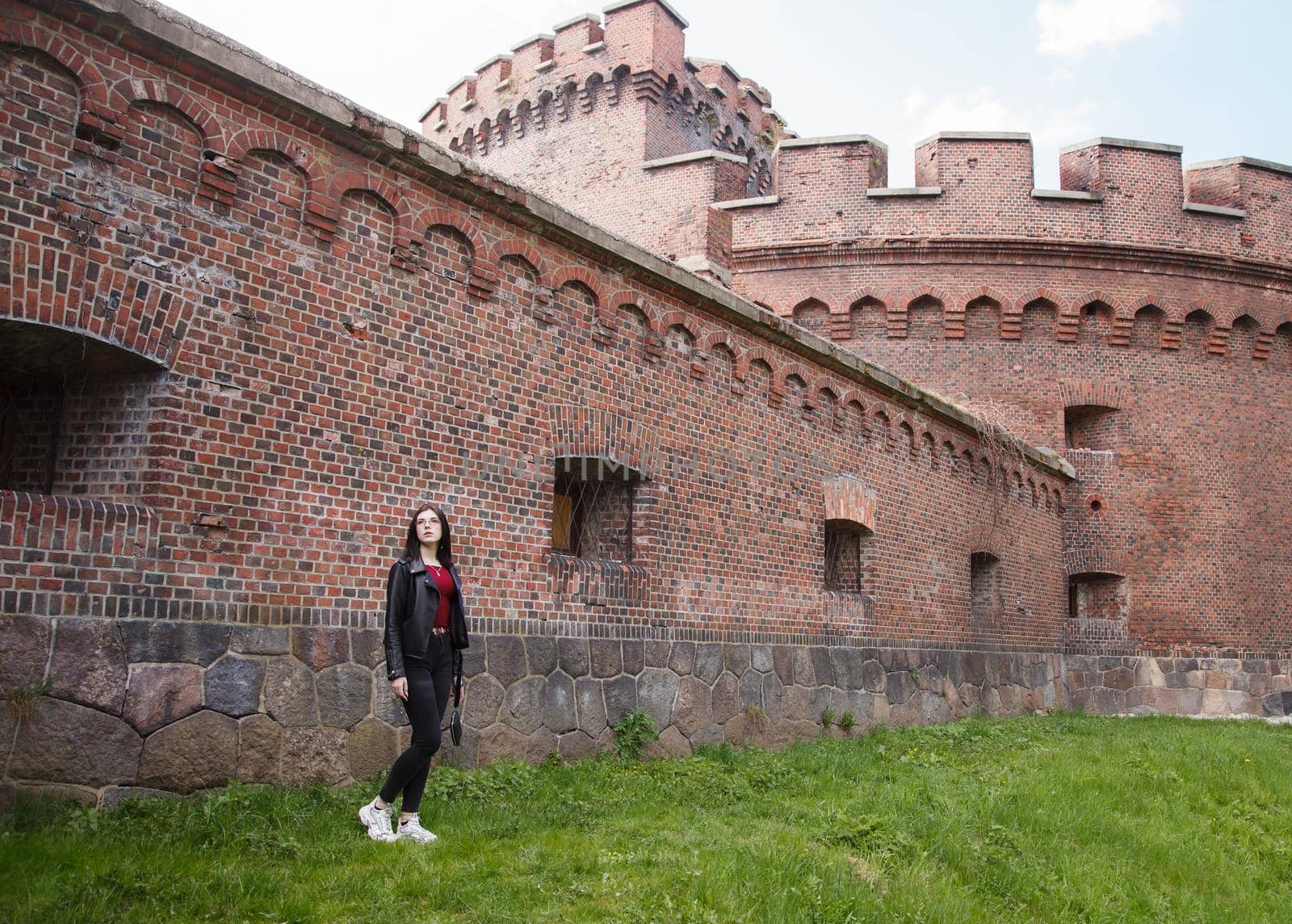 young beautiful girl stands near the old fortress wall by raddnatt