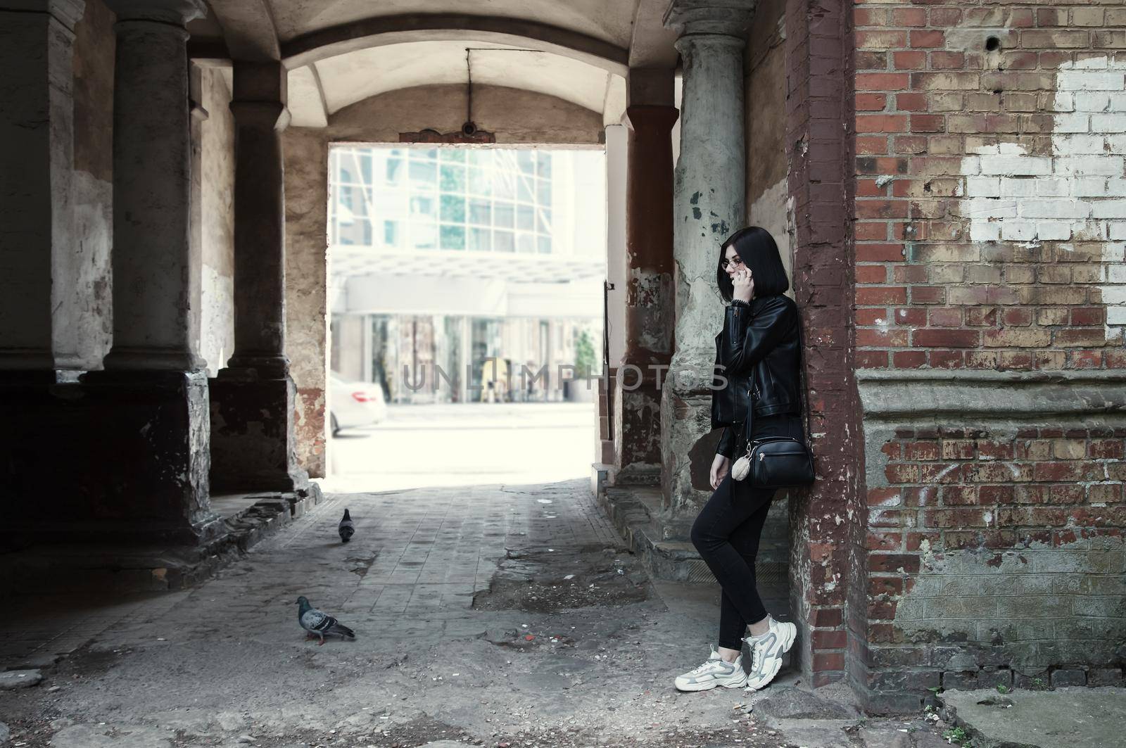 sad young girl stands in old arch on city street by raddnatt