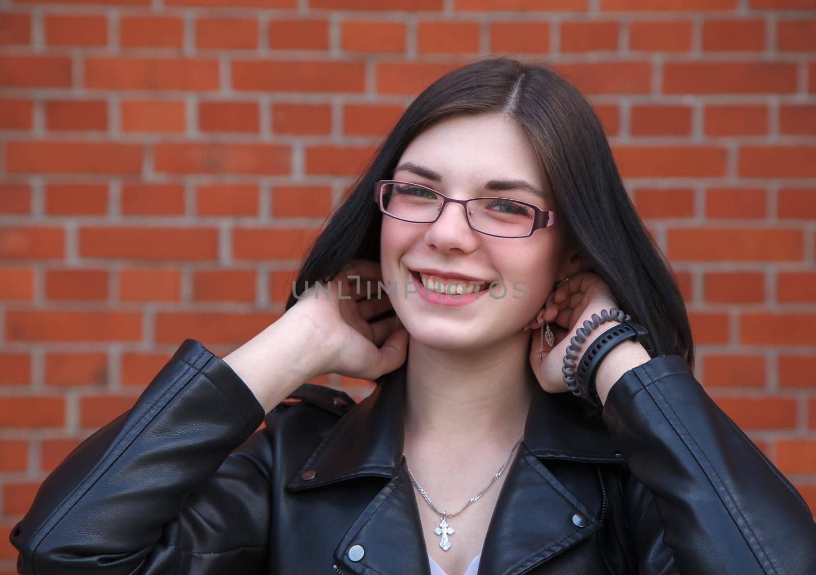 portrait of young beautiful brunette smiling girl near brick wall. closeup outdoor