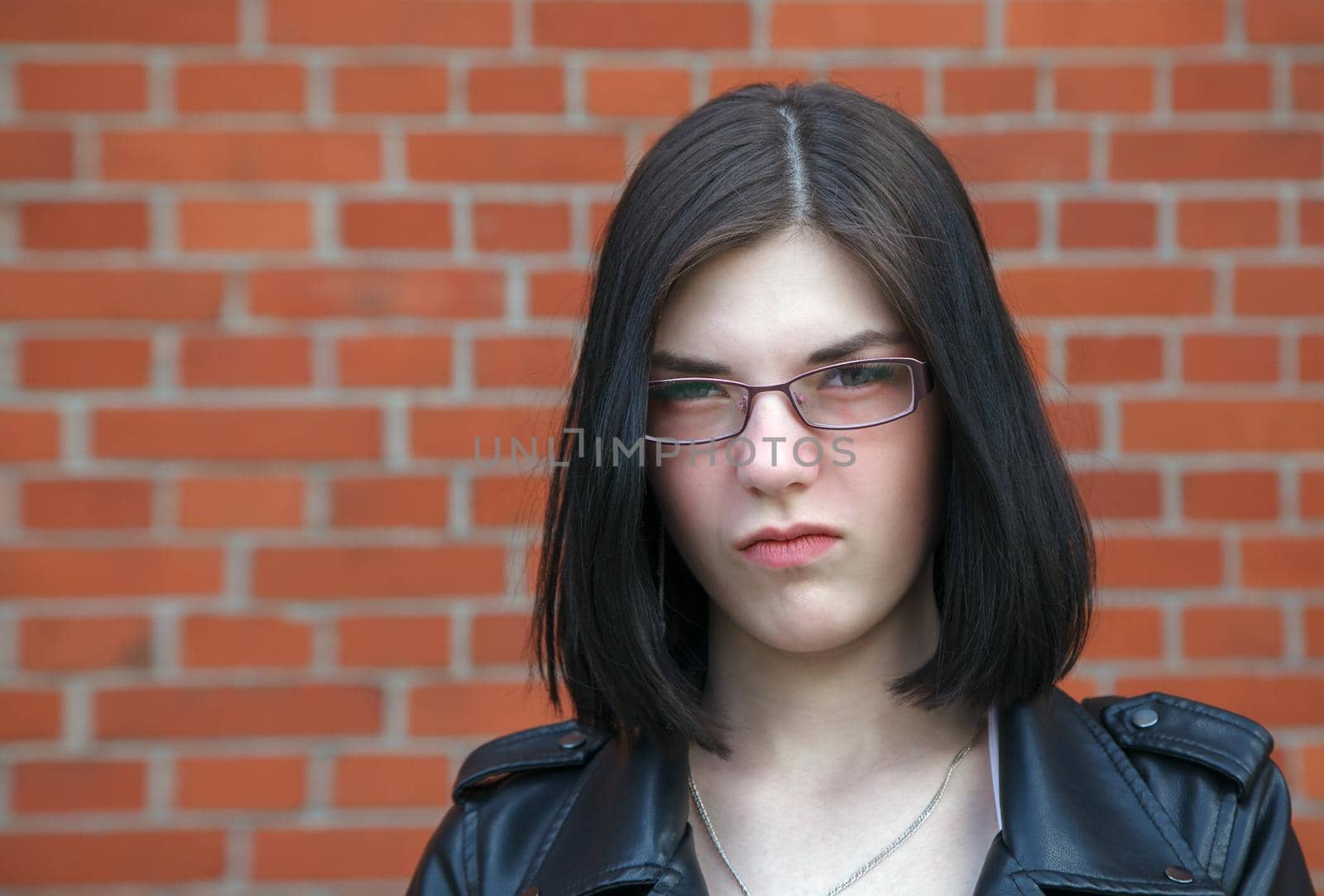 portrait of young beautiful brunette disgruntled girl near brick wall. closeup outdoor