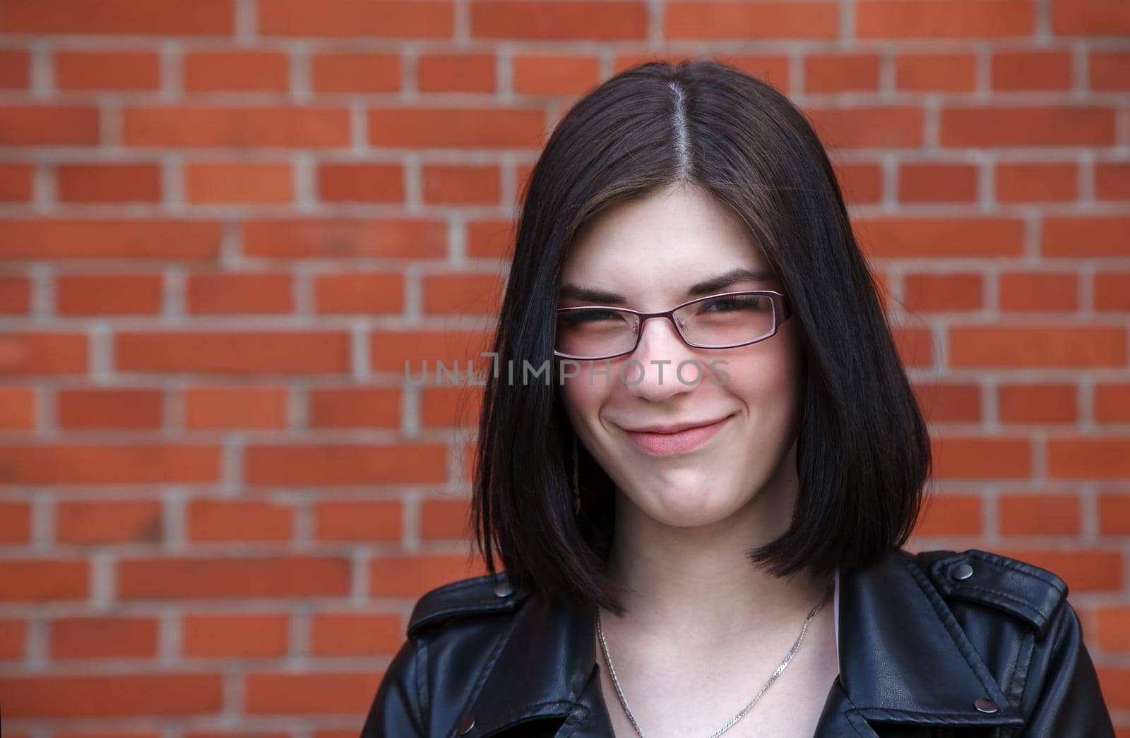 portrait of young beautiful brunette smiling girl near brick wall. closeup outdoor