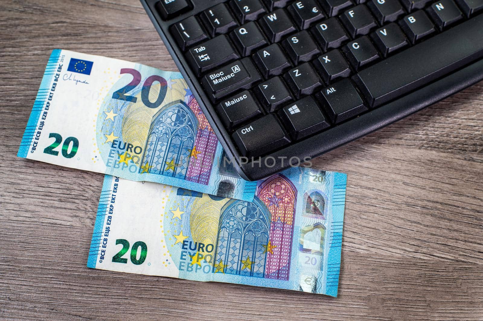 20 euro bills and computer keyboard on wooden background