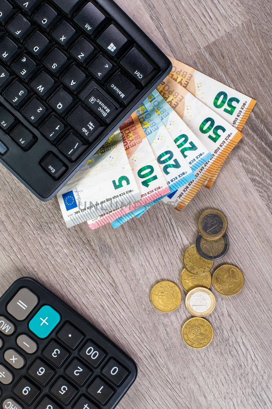 computer keyboard with euro money and calculator on wooden background