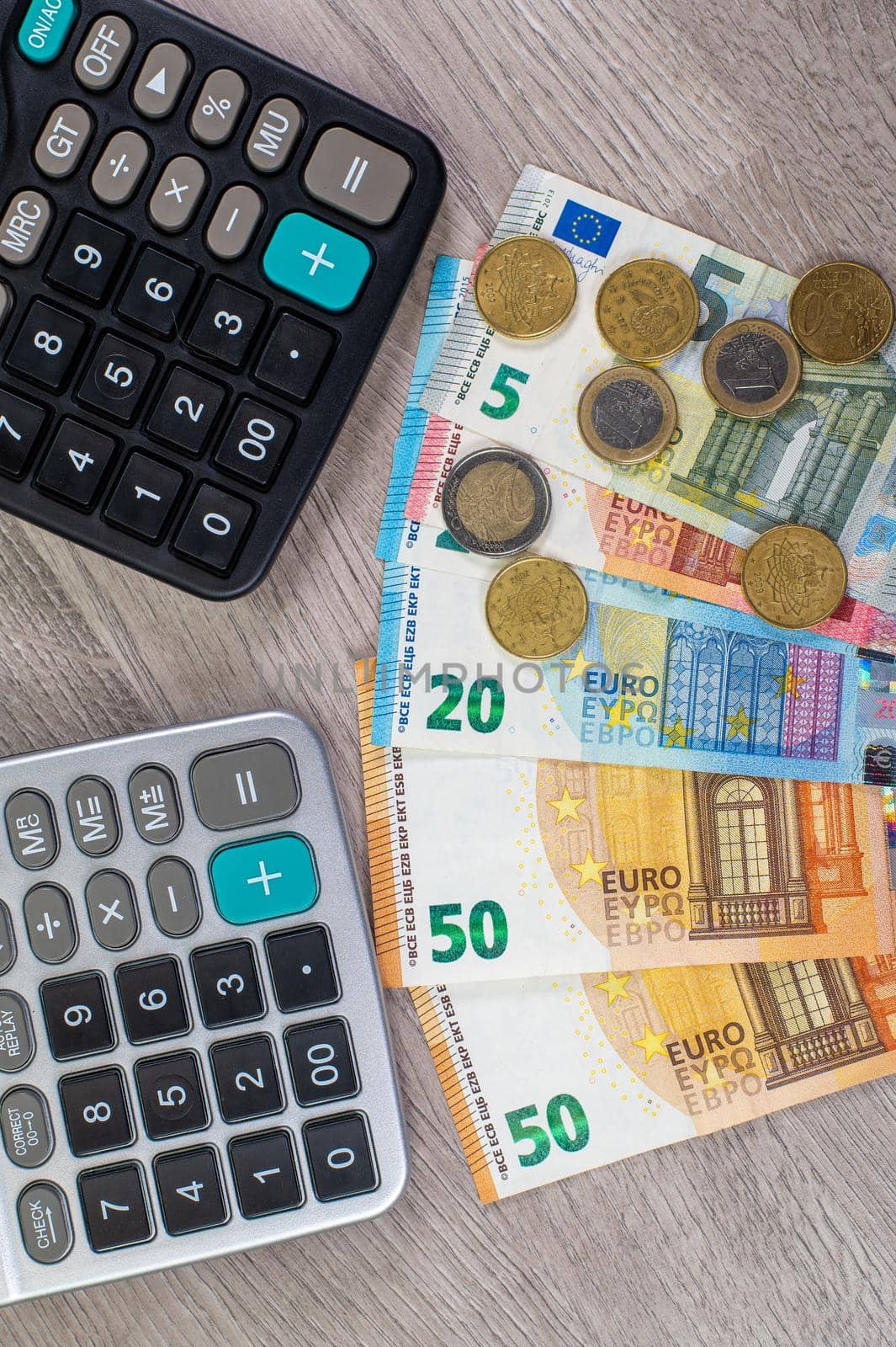 euro money of different denominations and calculators on wooden background