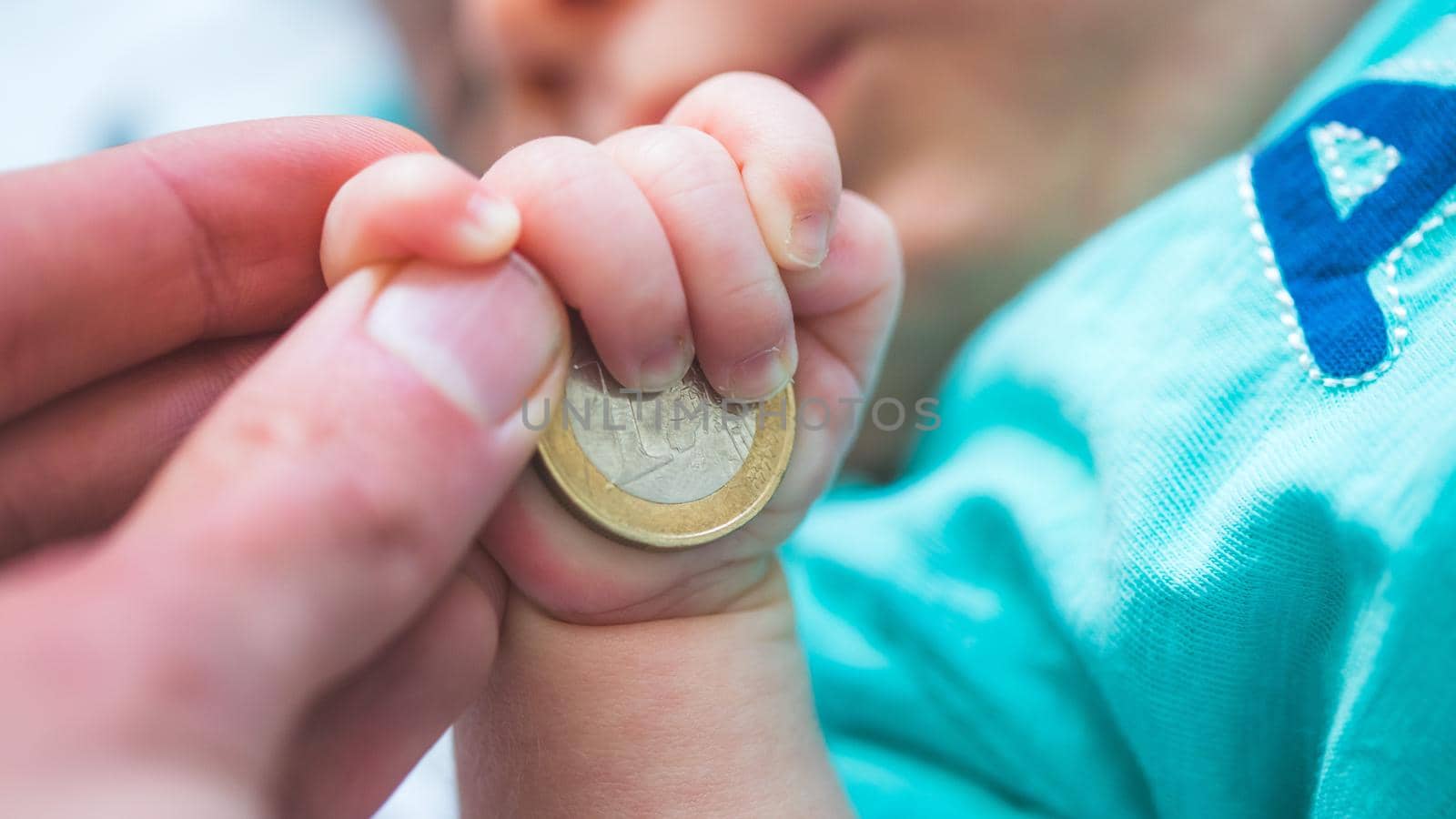 Close up of newborn baby hands holding a coin, retirement arrangement concept