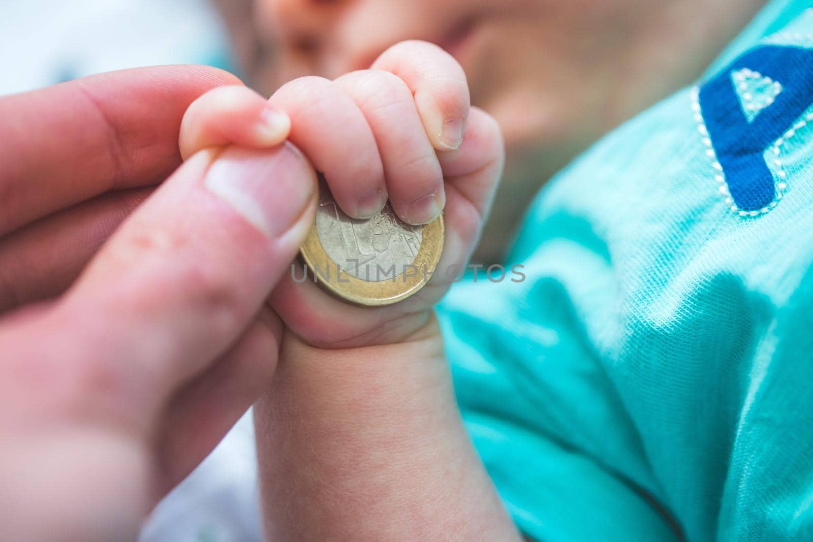 Old age insurance baby concept: Close up of newborn baby holding a coin by Daxenbichler
