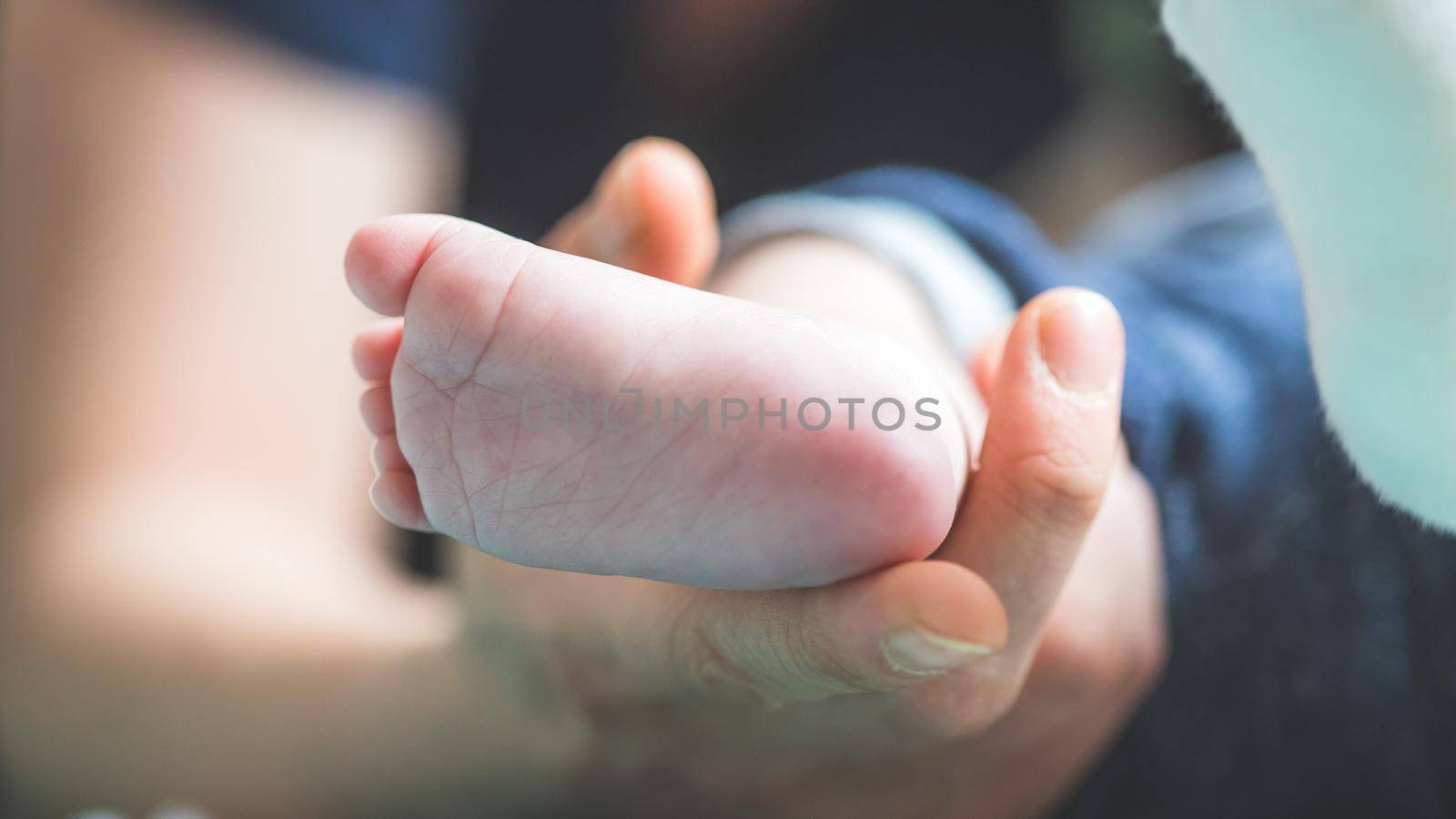 Close up of mother’s hands, holding newborn baby feet.