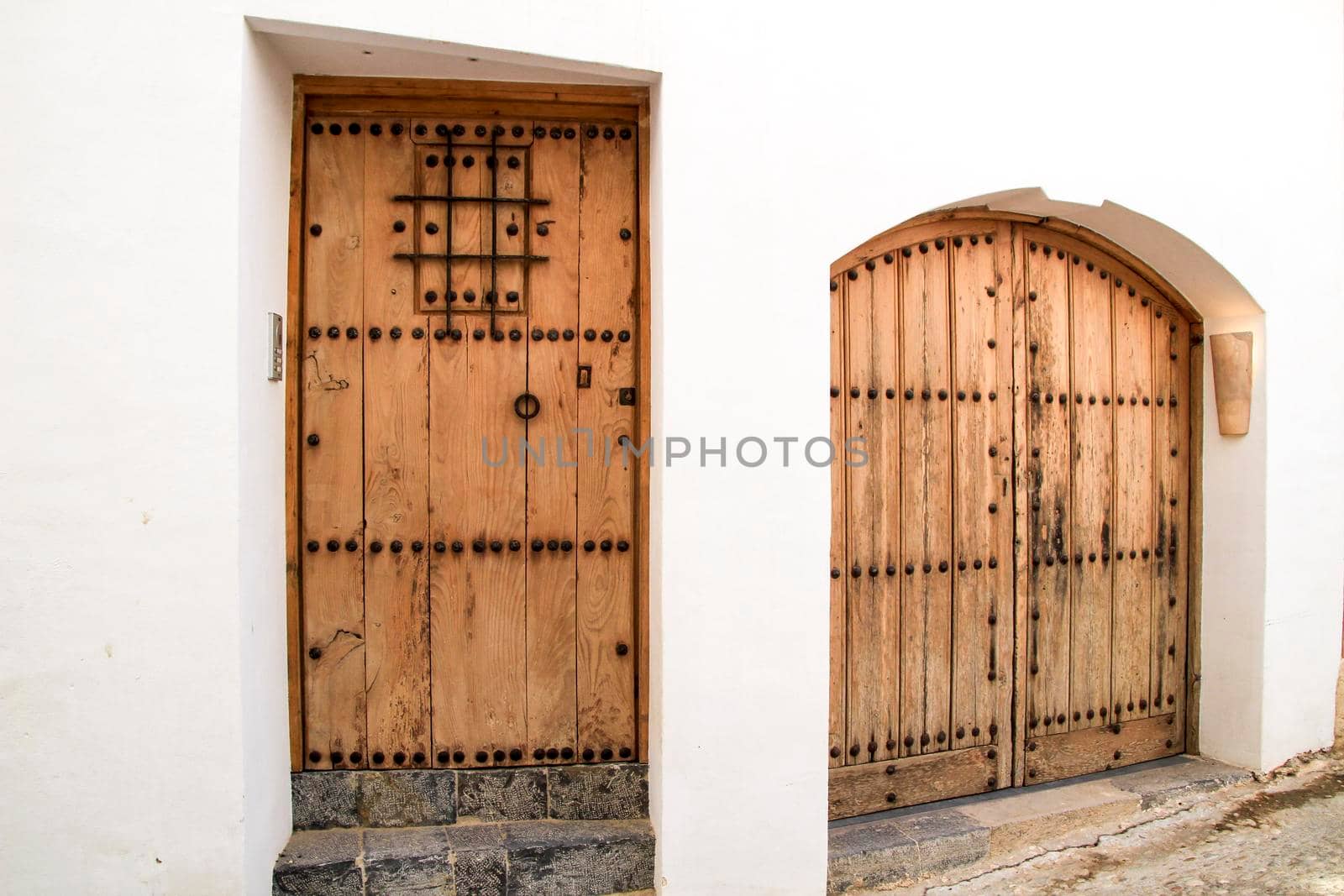 Beautiful whitewashed facade with old wooden door with iron details in Altea village, Alicante, Spain