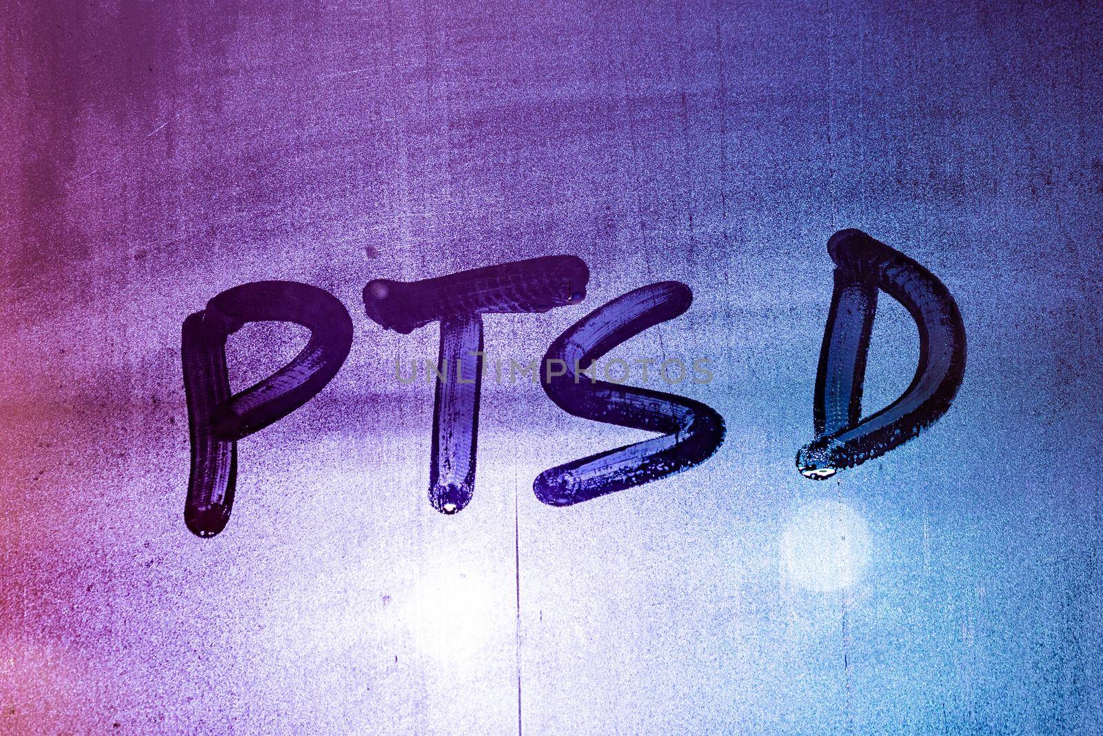 abbreviation ptsd - post traumatic stress disorder - handwritten on night wet window glass, close-up with selective focus