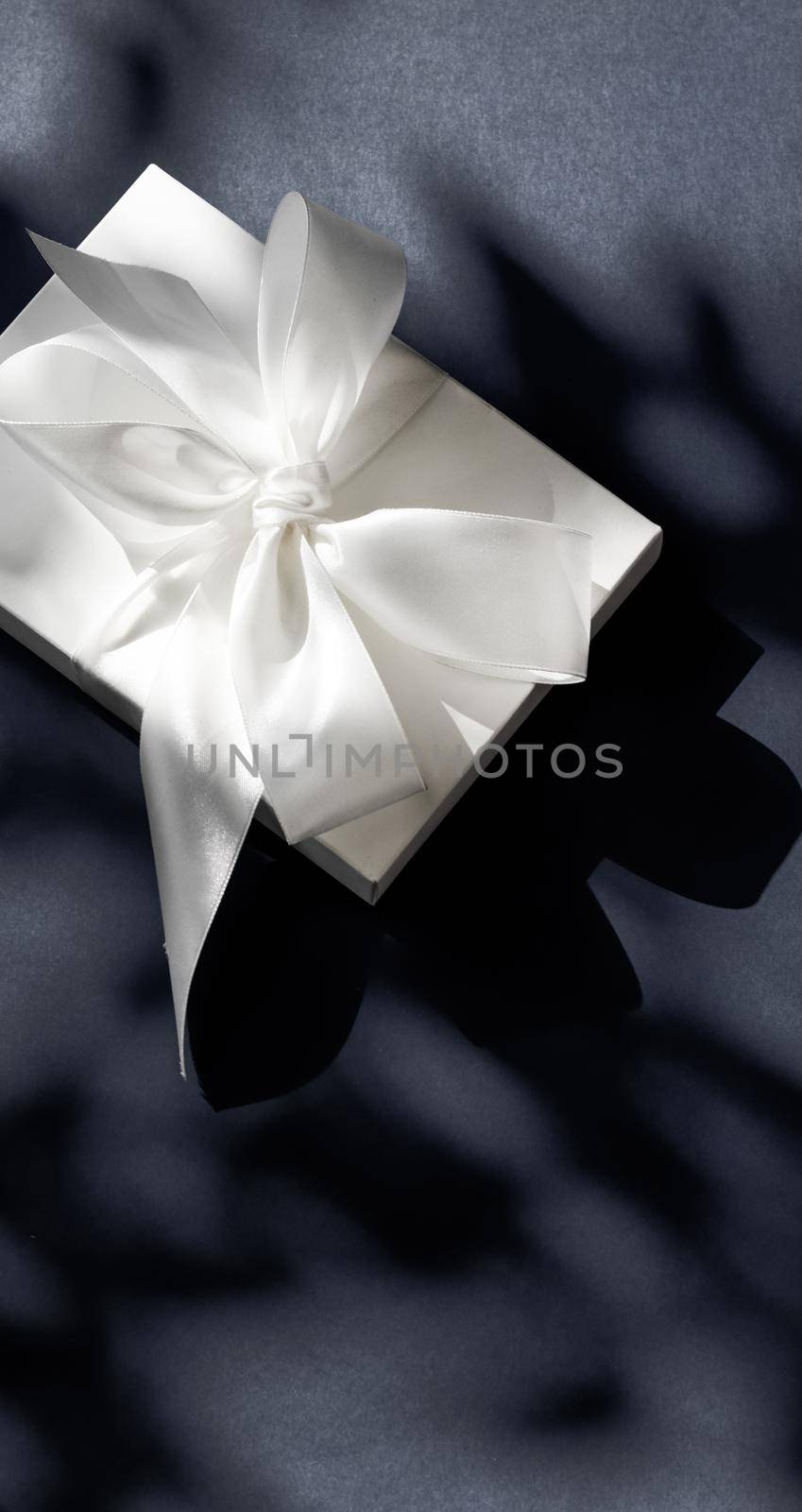 Anniversary celebration, shop sale promotion and luxe surprise concept - Luxury holiday white gift box with silk ribbon and bow on black background, luxe wedding or birthday present