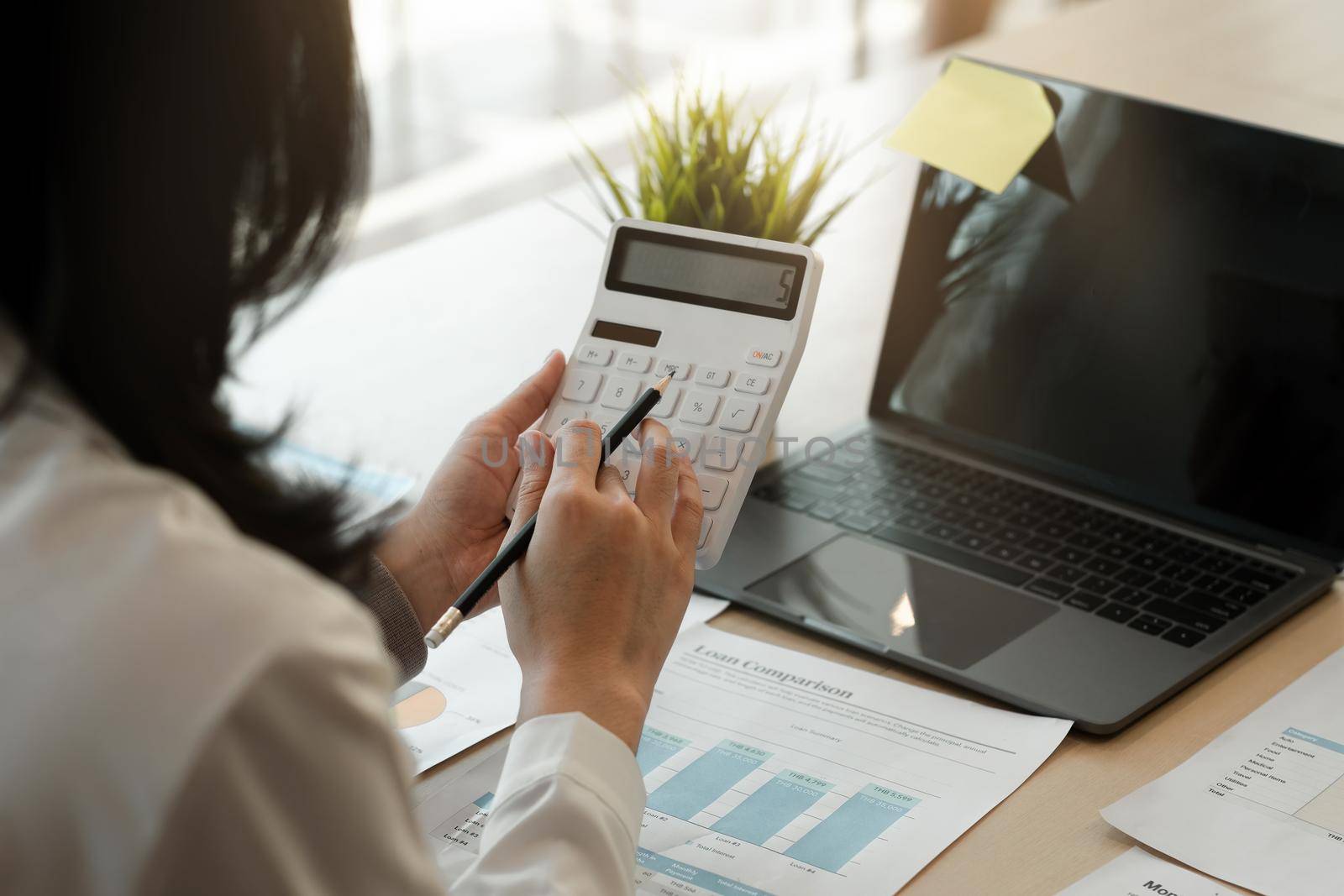 businesswoman working on desk office with using a calculator to calculate the numbers, finance accounting concept. by nateemee