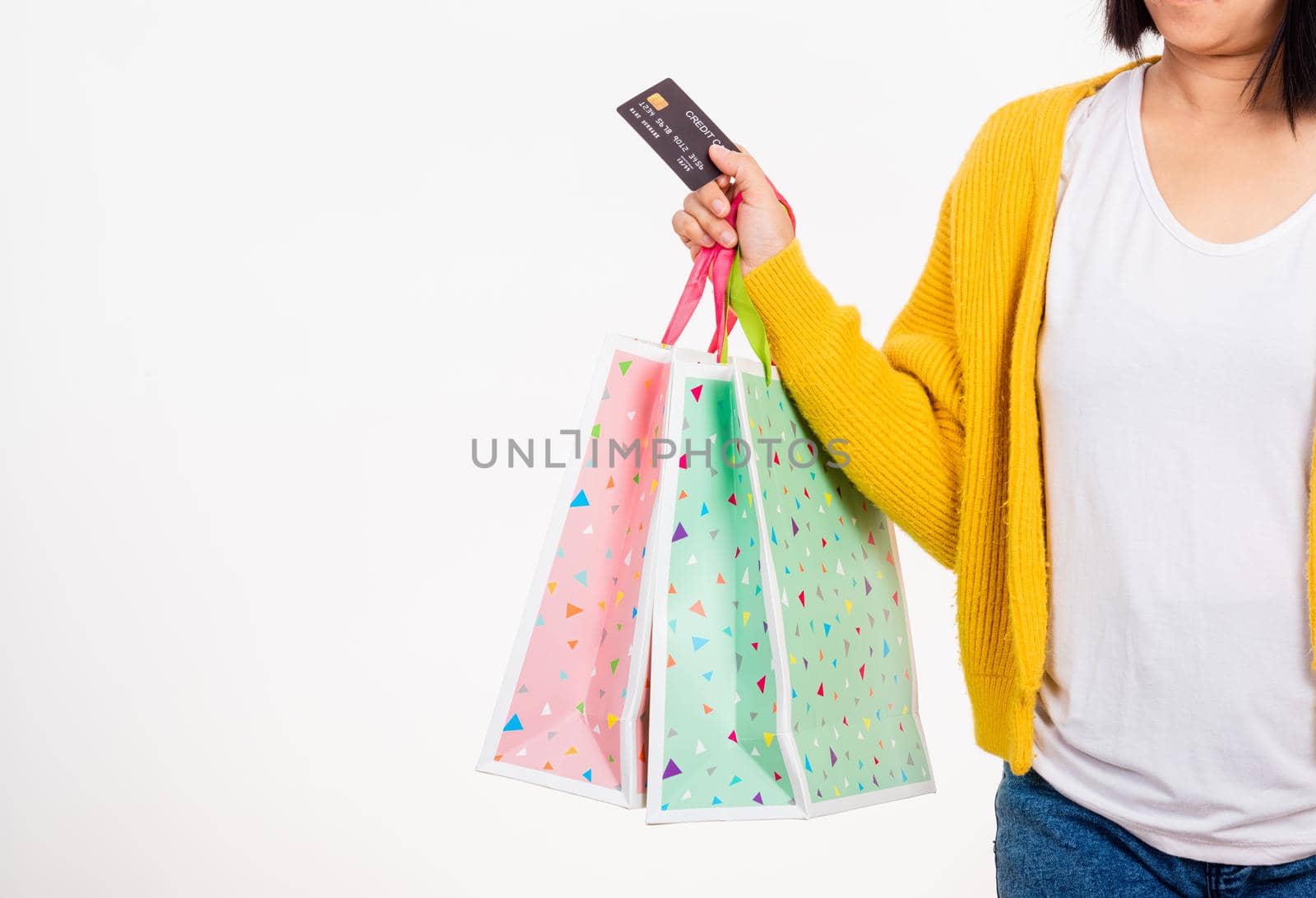 Happy woman hand she wears yellow shirt holding shopping bags multicolor and credit card, young female hold many packets within arms isolated on white background, Black Friday sale concept