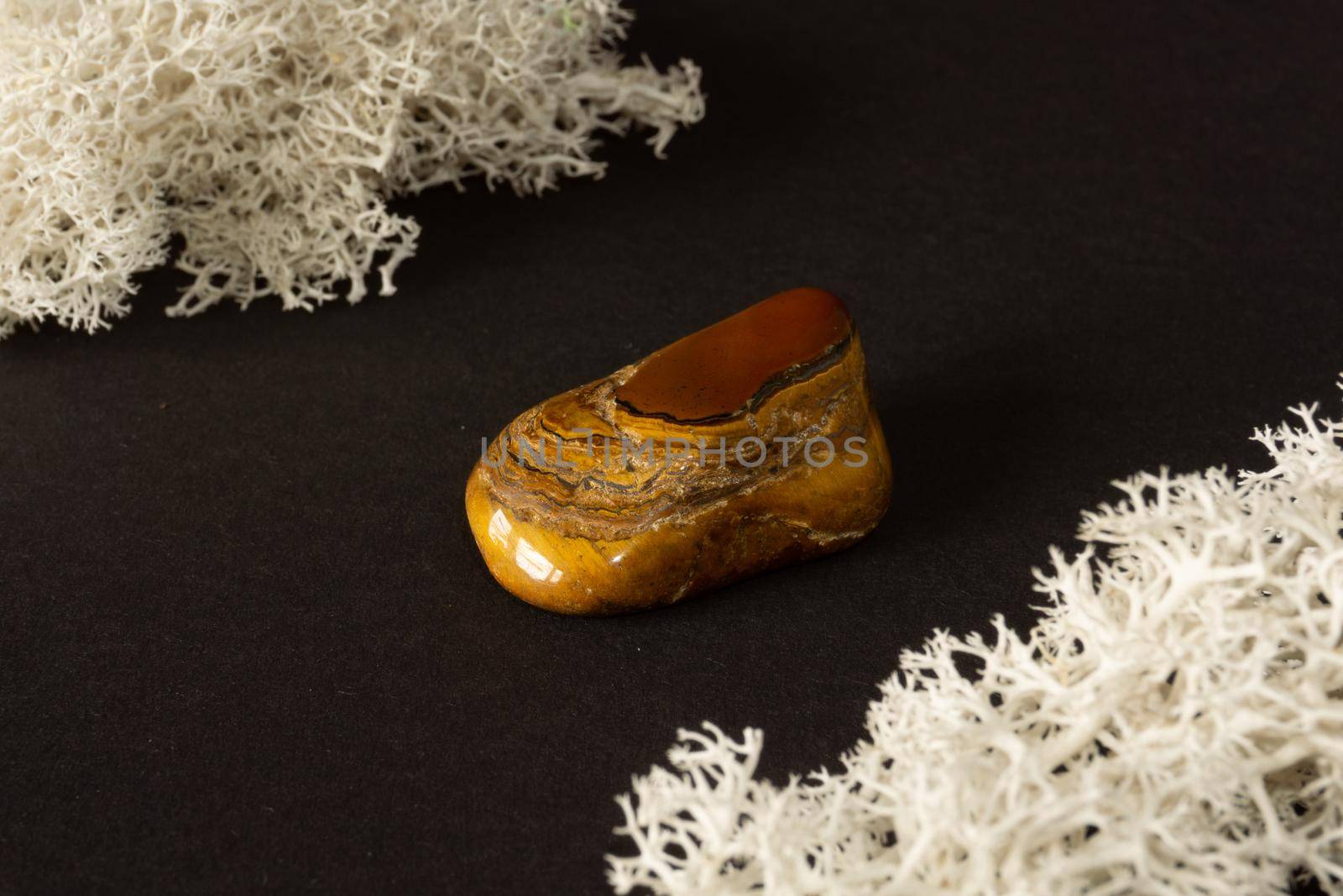 Tiger's eye stone from Republic of South Africa RSA. Natural mineral stone on black background. Mineralogy, geology, magic of stones, semi-precious stones and samples of minerals. Close-up macro photo.