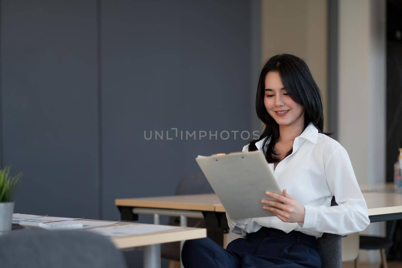 Portrait of successful young Asian businesswoman working with financial report at her office by nateemee