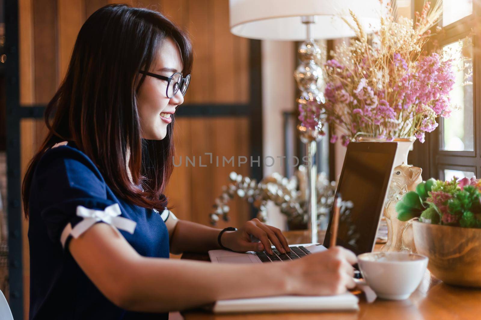 Asian business female working with laptop make a note in coffee shop like the background. by tinapob2534