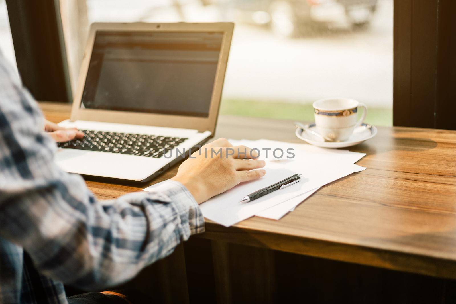 Close-up of businessman working with laptop computer on in coffee shop like the background.