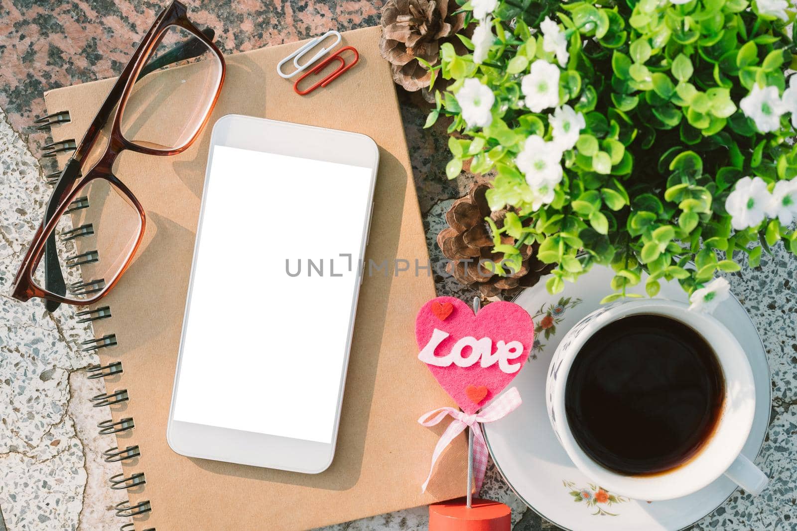 Top view image of empty notebook,smartphone,spectacles and cup of coffee on Marble floor background. Love concept with heart desktop,Valentine's Day.