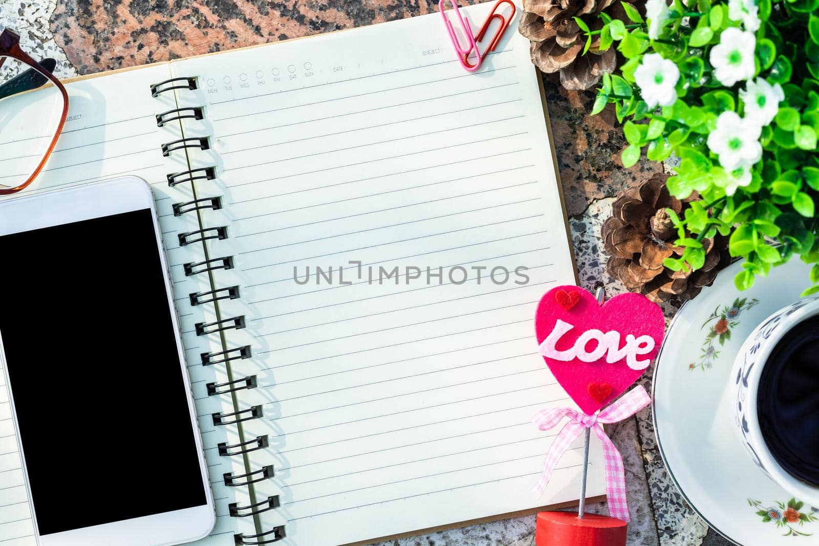 Top view image of empty notebook,smartphone,spectacles and cup of coffee on Marble floor background. Love concept with heart desktop,Valentine's Day. by tinapob2534