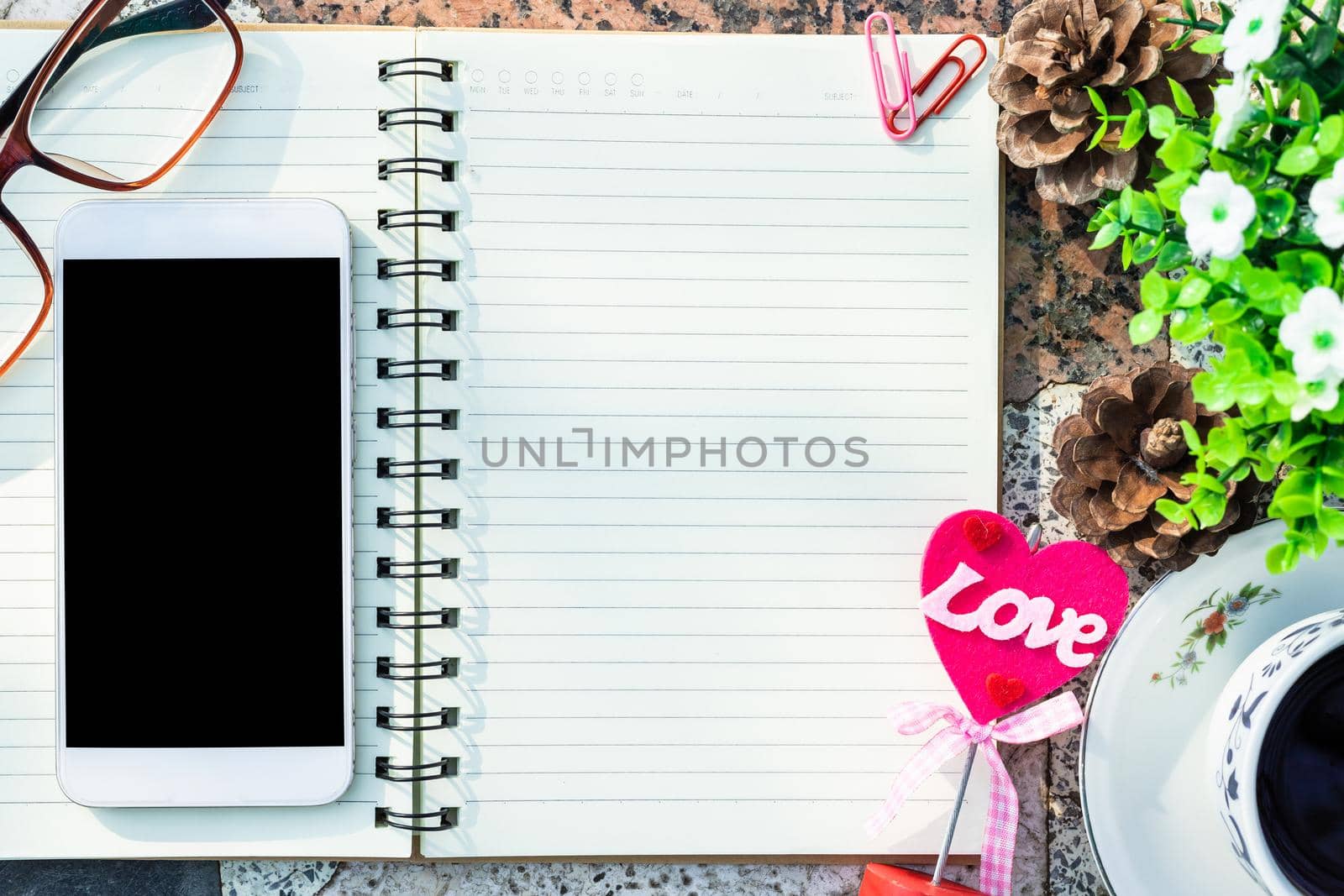 Top view image of empty notebook,smartphone,spectacles and cup of coffee on Marble floor background. Love concept with heart desktop,Valentine's Day.