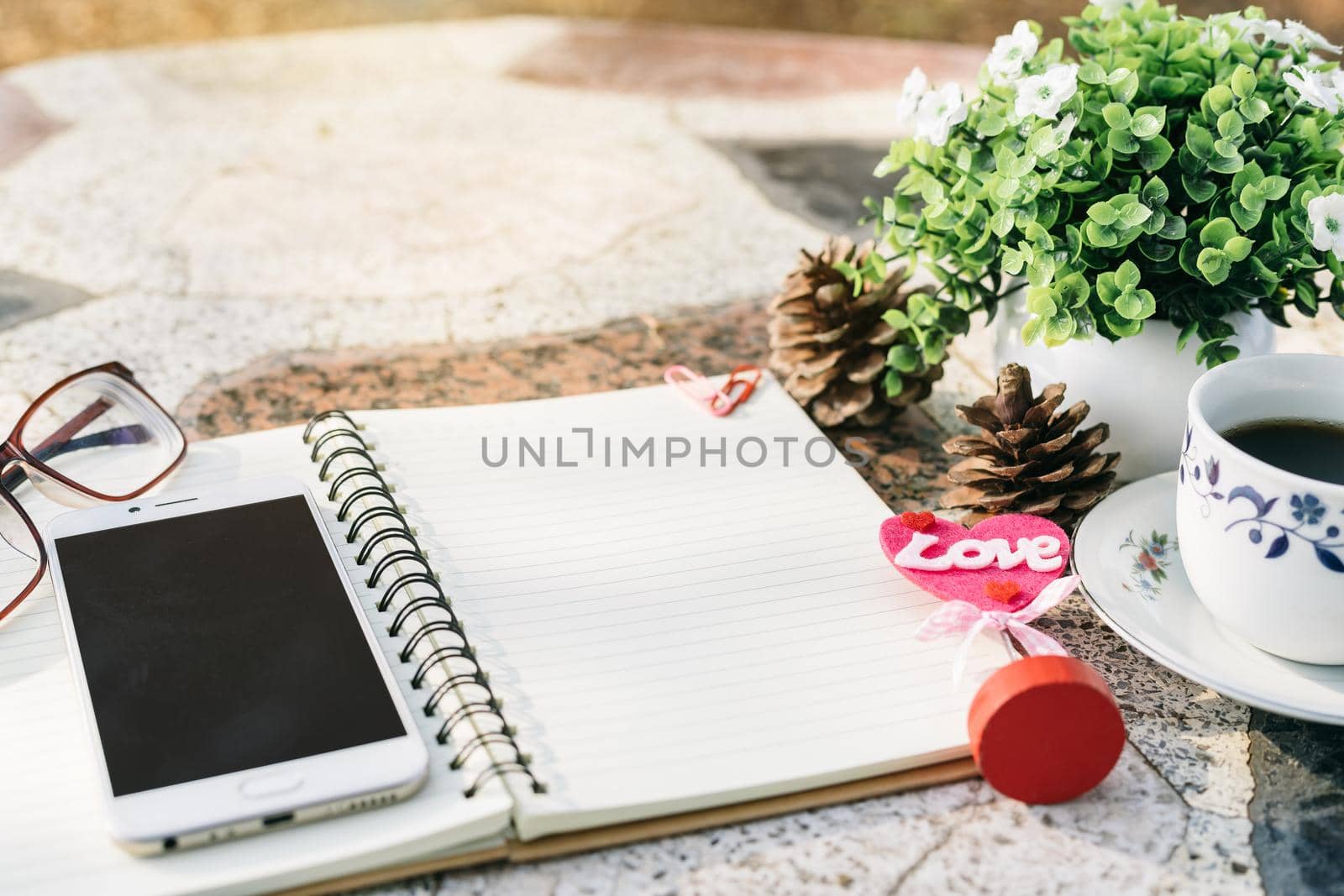 Close-up of empty notebook,smartphone,spectacles and cup of coffee on Marble floor background. Love concept with heart desktop,Valentine's Day.