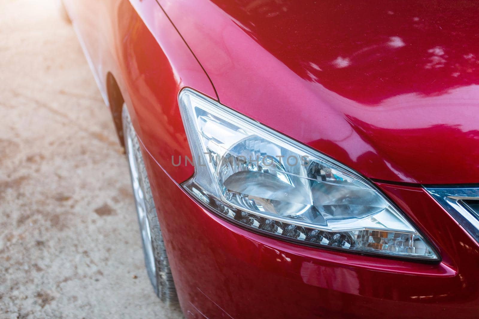Closeup of headlight ,window of red car outdoors.