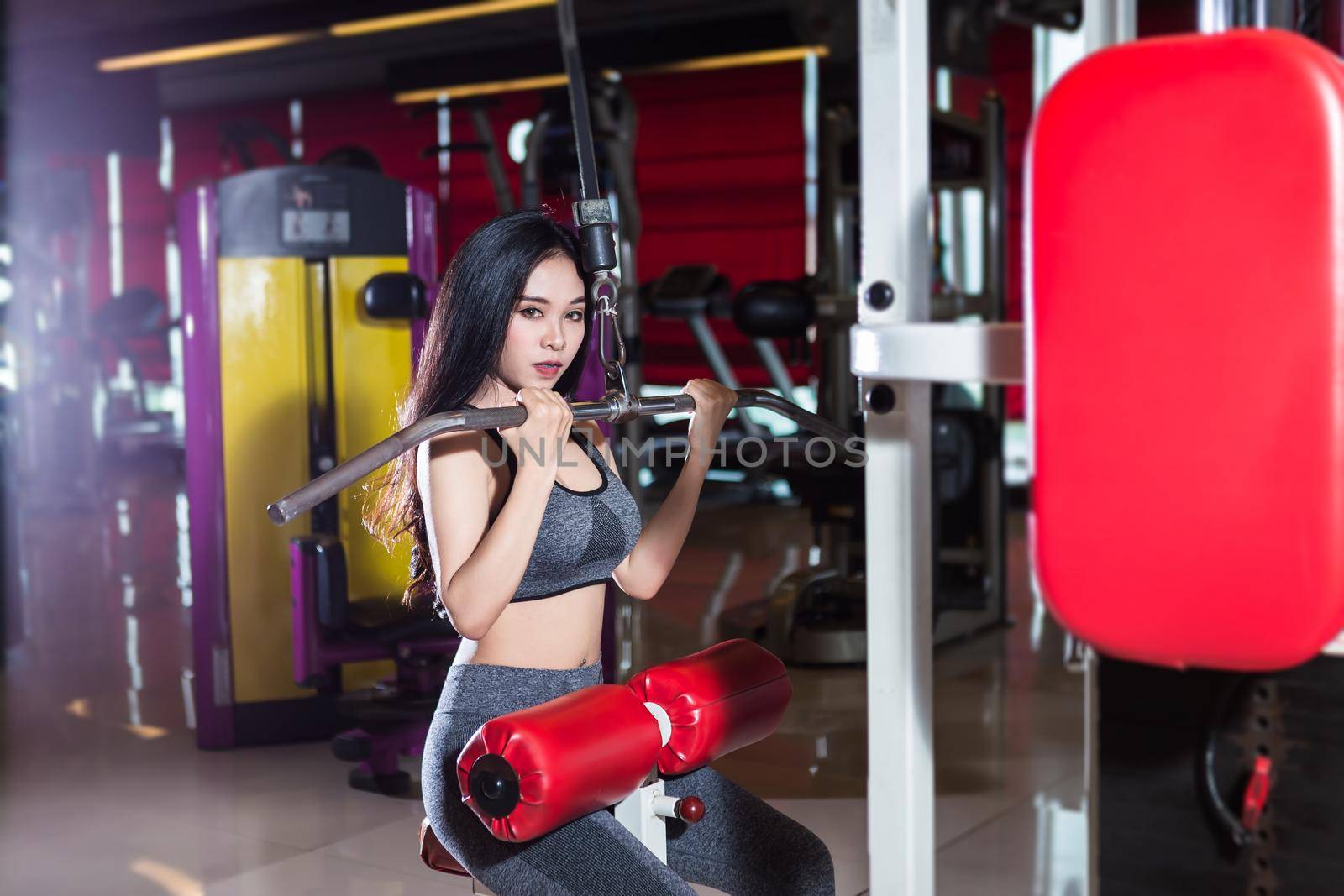 Fitness Asian women performing doing exercises training the shoulder and chest muscles in sport gym interior and health club. by tinapob2534
