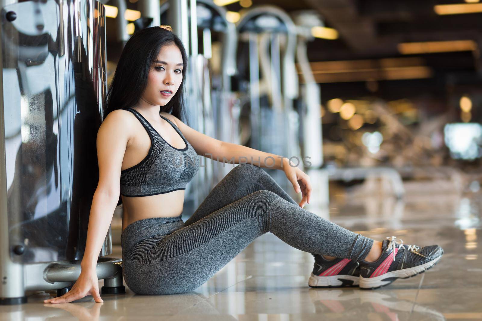 Fitness Asian women sitting in sport gym interior and fitness health club with sports exercise equipment Gym background. by tinapob2534