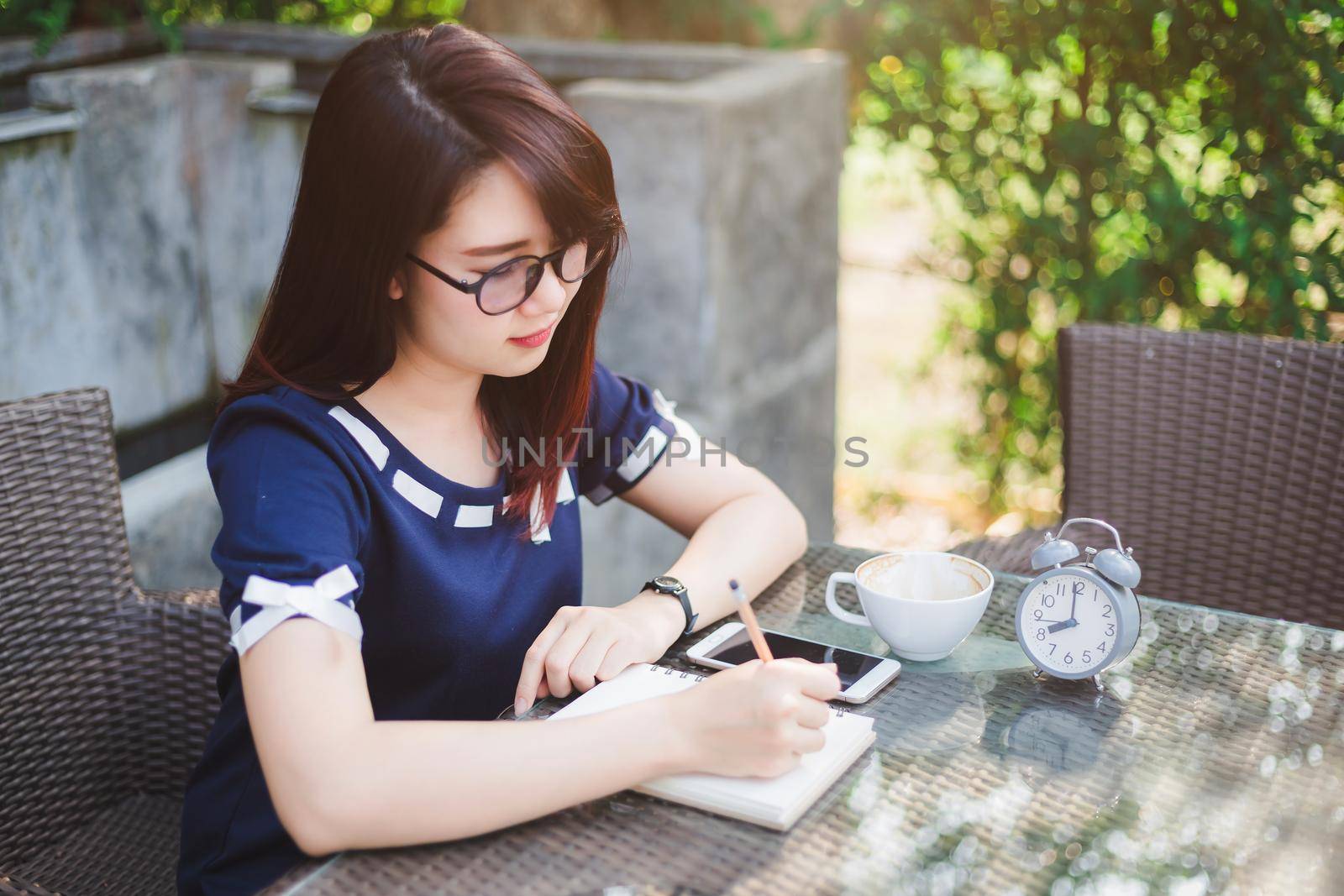 Asian young business woman between the thinking working make a note of something making and clock in summer park or office outdoor.